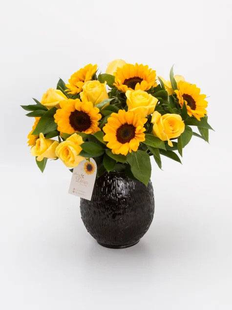 Arranjo de girassol e rosas amarelas no vaso preto